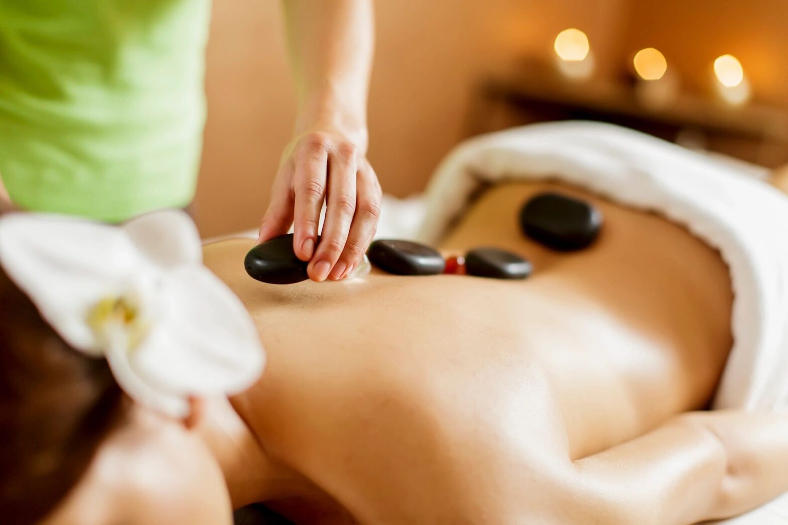 Massage Therapist applying hot stones along the spine
